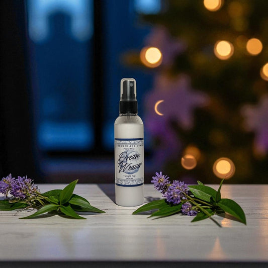 Spray bottle labeled 'Dream Weaver' with purple flowers on a table, blurred lights in the background